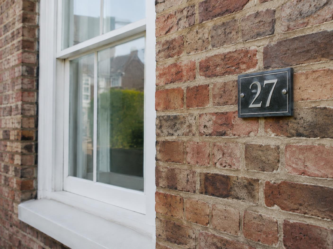 Brick wall, sash window and house number on a British home