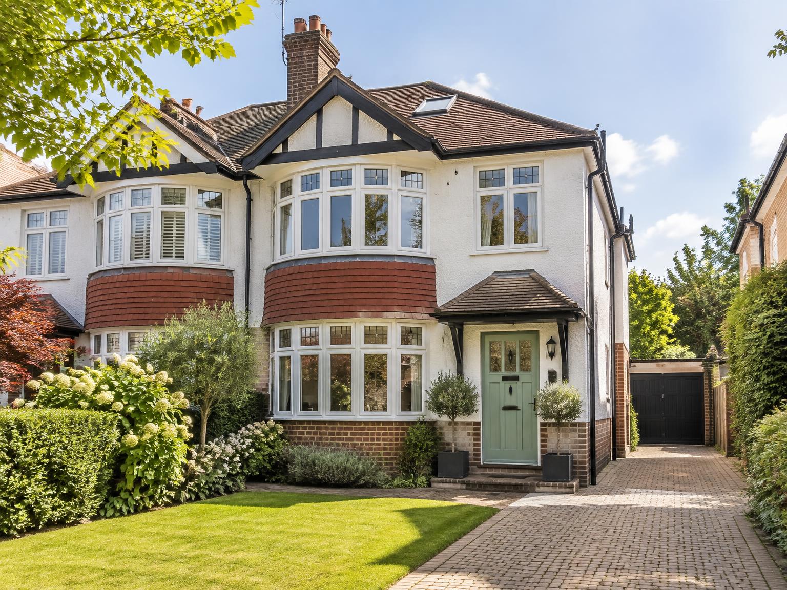 A well-kept British home with its front door, windows, garden and roof visible